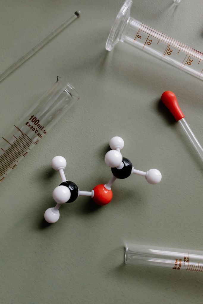 Close-up of a molecular model surrounded by laboratory equipment like pipettes and test tubes.